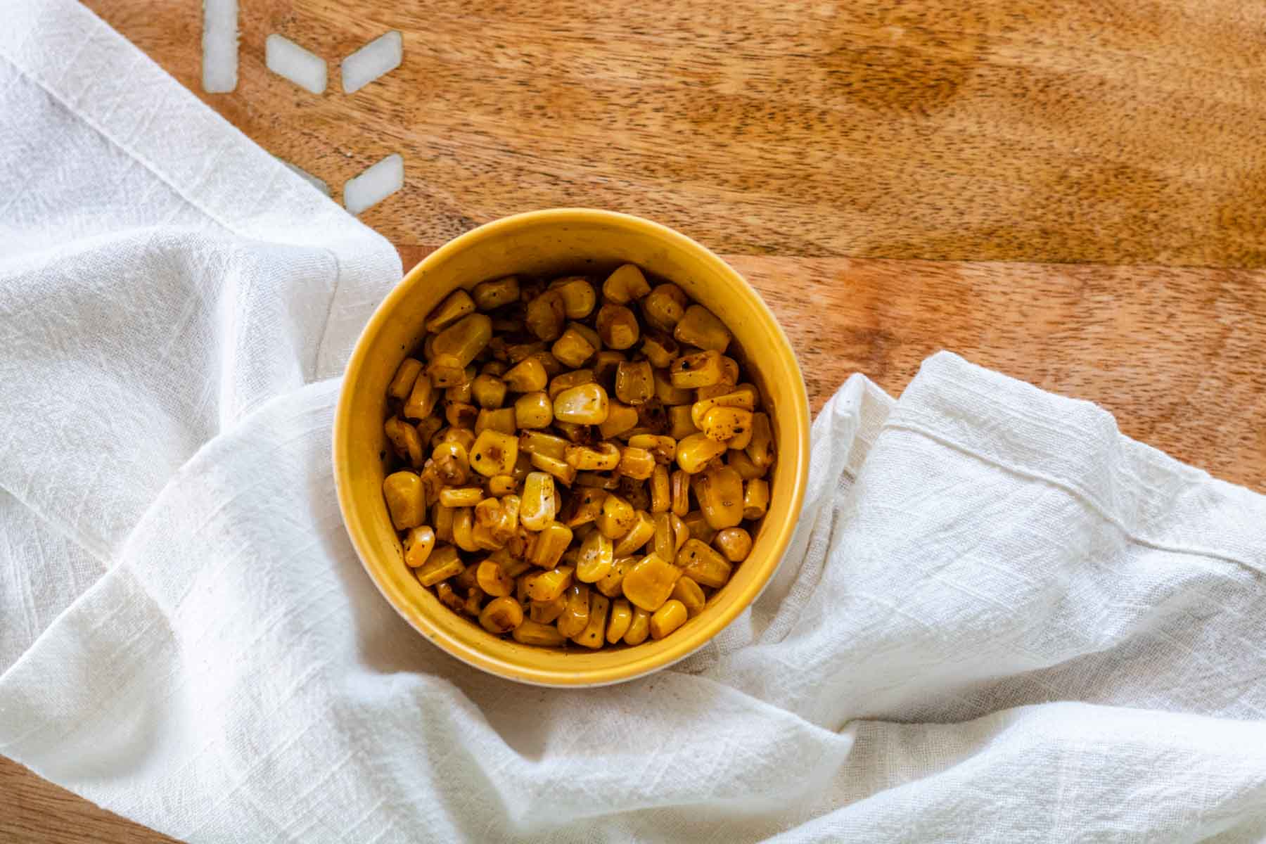 Charred corn in a yellow bowl.