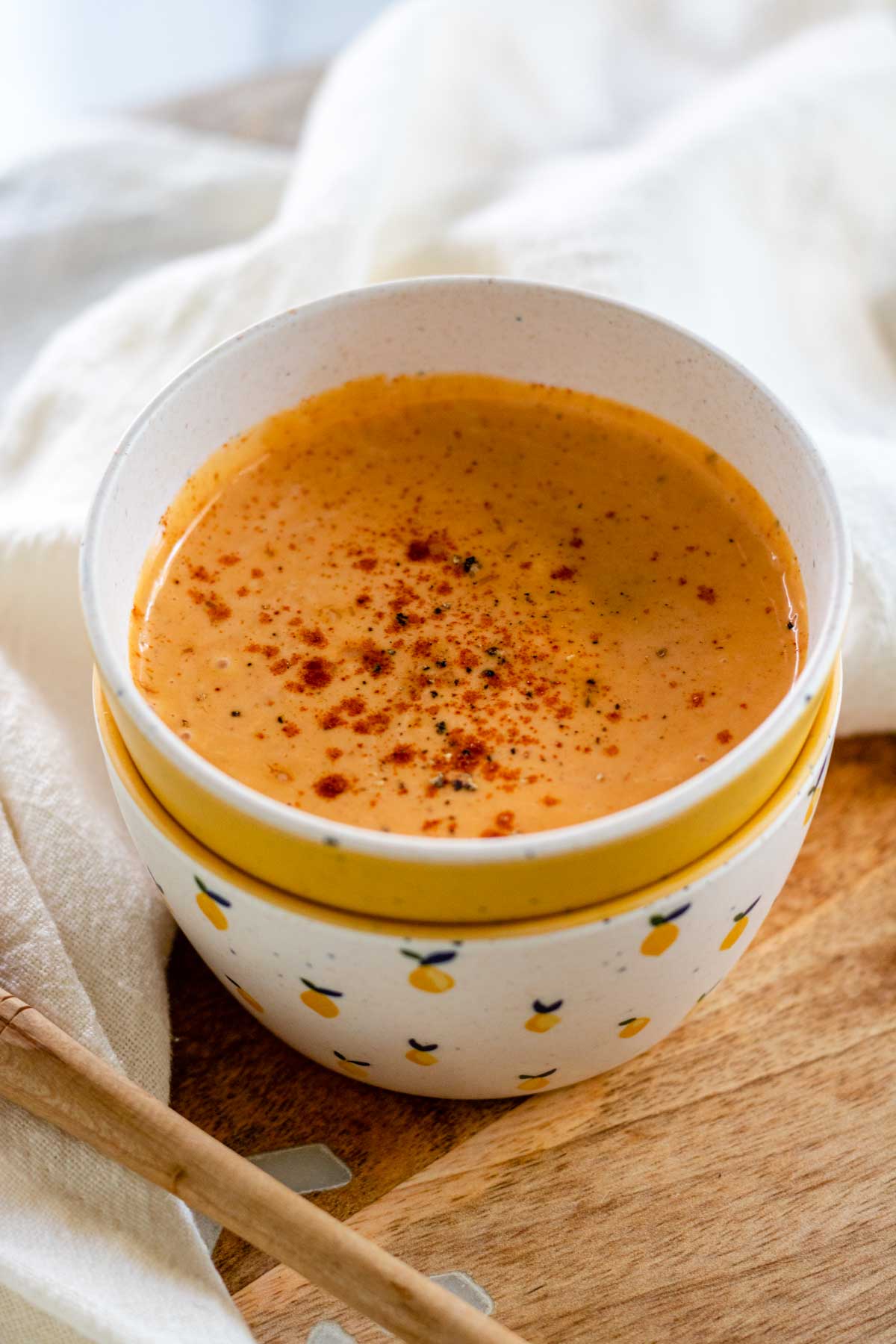 A bowl with an orange sauce and paprika sprinkled on top.