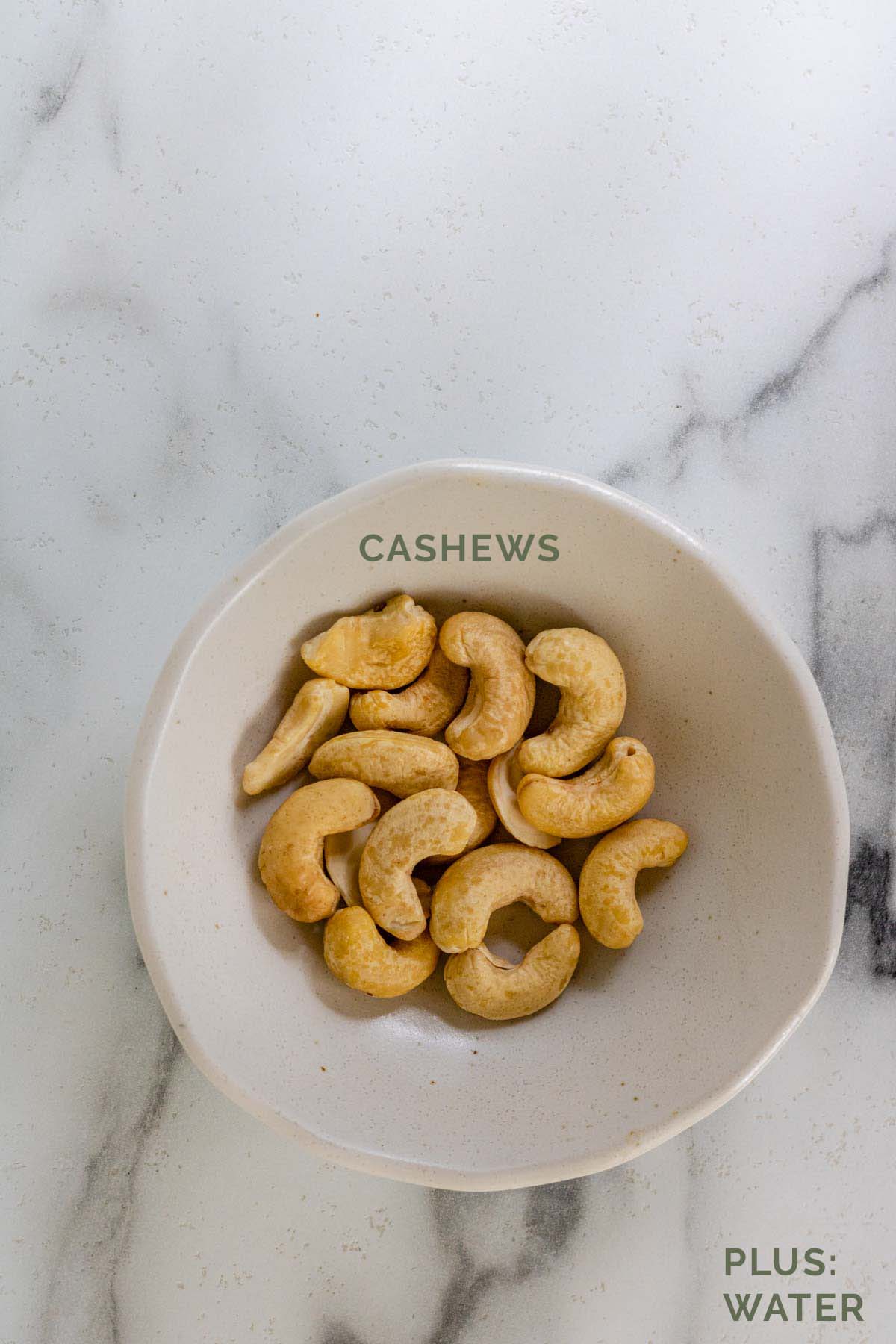 Cashews in a white bowl with text label for Pinterest.