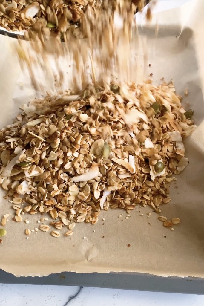Granola is poured onto a parchment paper lined pan.