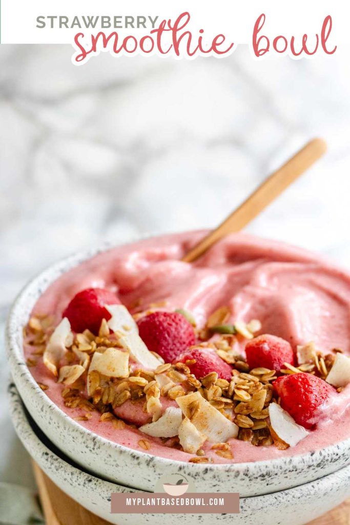 A pink smoothie bowl with strawberries and granola on top with a text title for pinterest.