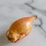 A whole shallot on a white marble counter with a text title for Pinterest.