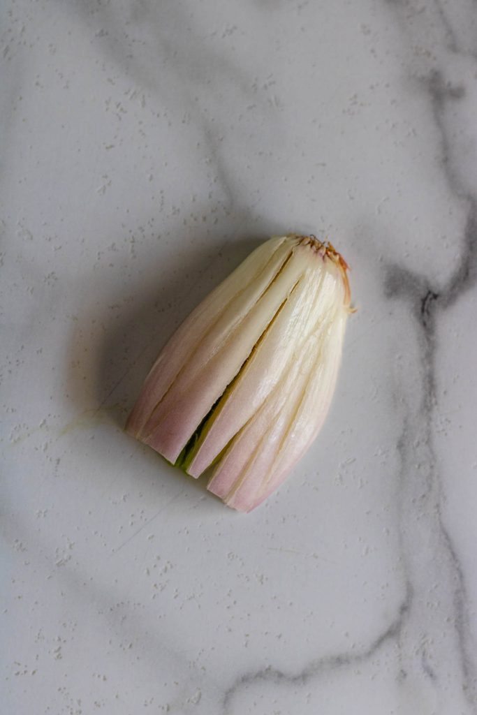 A shallot with long strips cut into it.