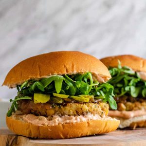 Chickpea burgers on buns with sauce, pickles, and arugula.