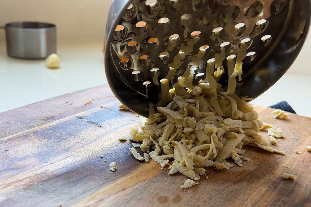 Grated tofu under a cheese grater.