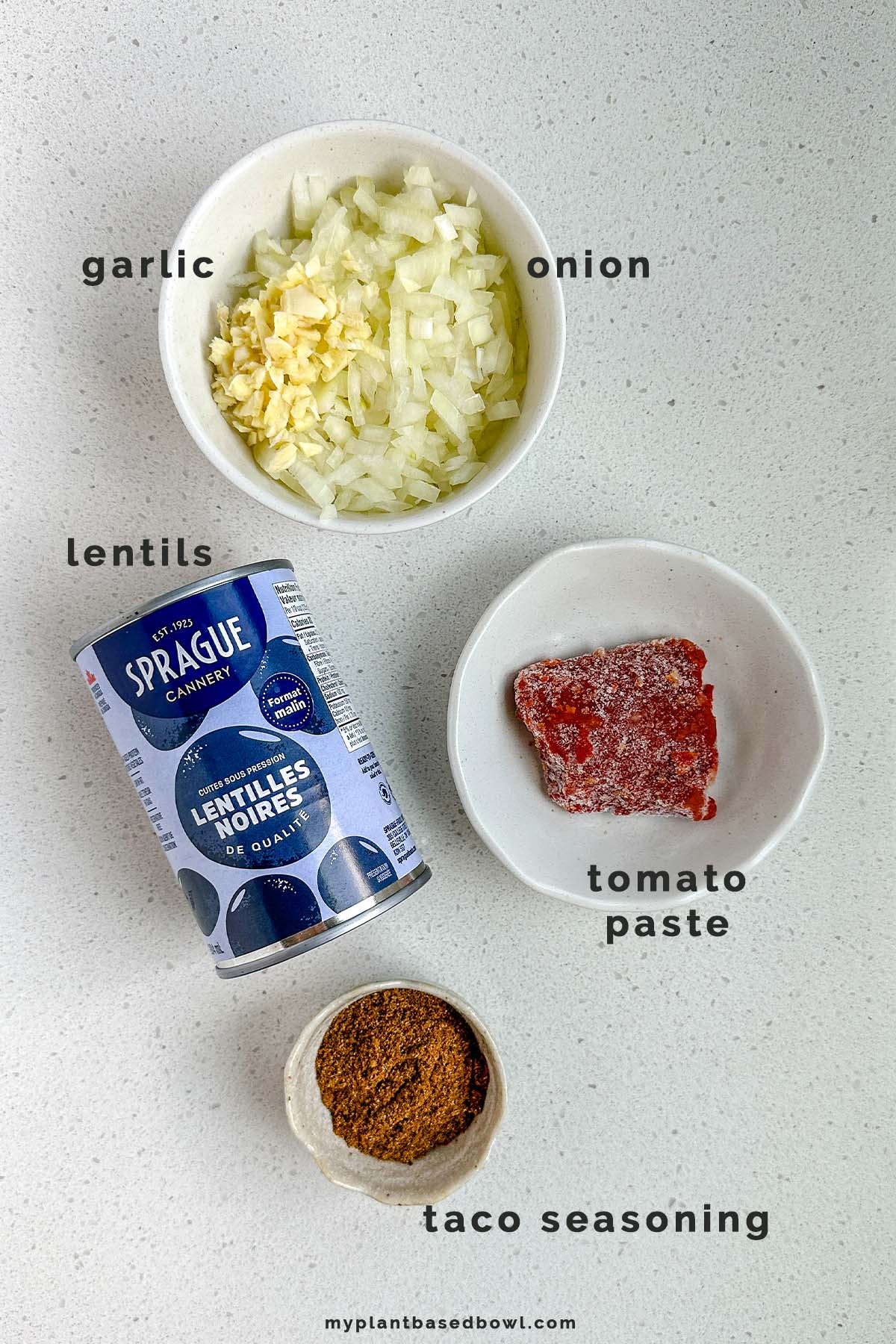 Ingredients on a counter, labeled garlic, onion, lentils, tomato paste, and taco seasoning.
