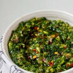 Green chunky sauce in a bowl with the text kale chimichurri.