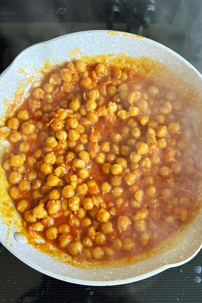 Chickpeas in buffalo sauce in a small skillet.