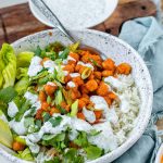 A bowl with rice, chickpeas, salad and a white sauce with the text buffalo chickpea bowls.