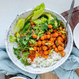 A bowl with rice, chickpeas, salad and a white sauce.