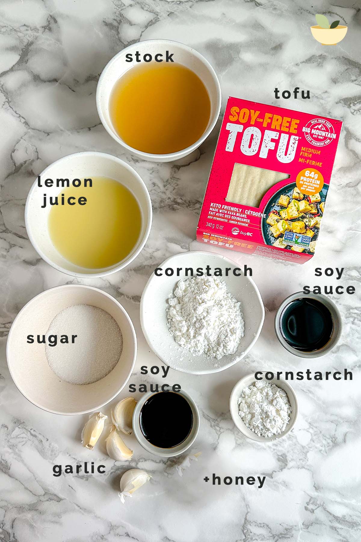 Ingredients for a saucy tofu recipe in bowls on a white marble counter, labeled.