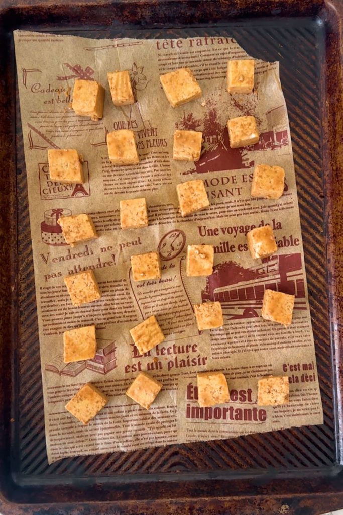 Tofu cubes on a parchment paper lined baking sheet.