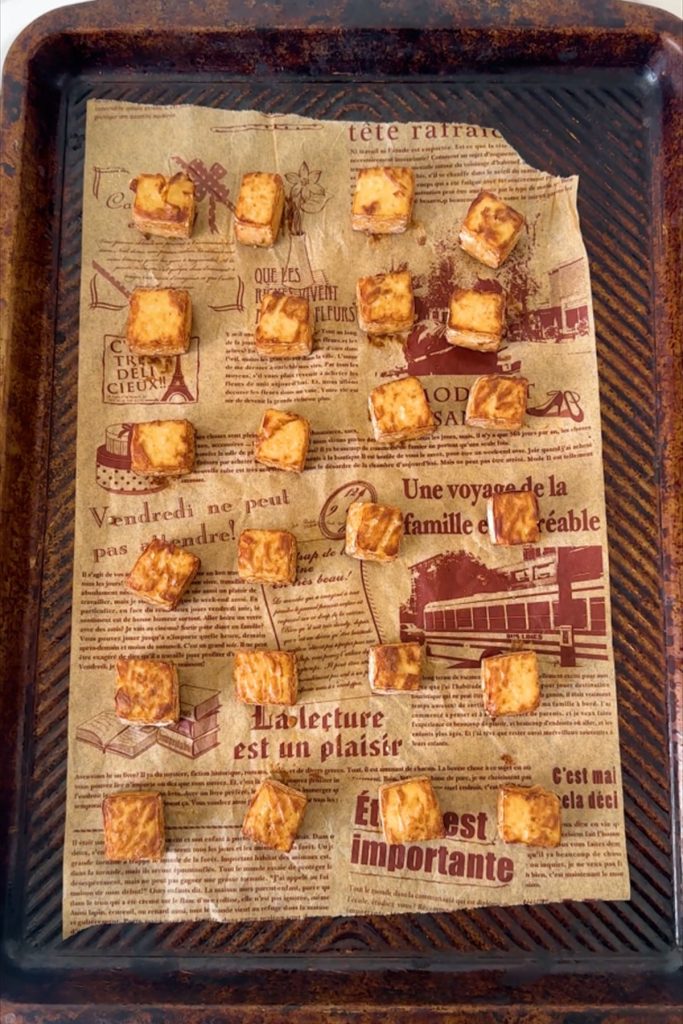 Tofu cubes on a parchment paper lined baking sheet.