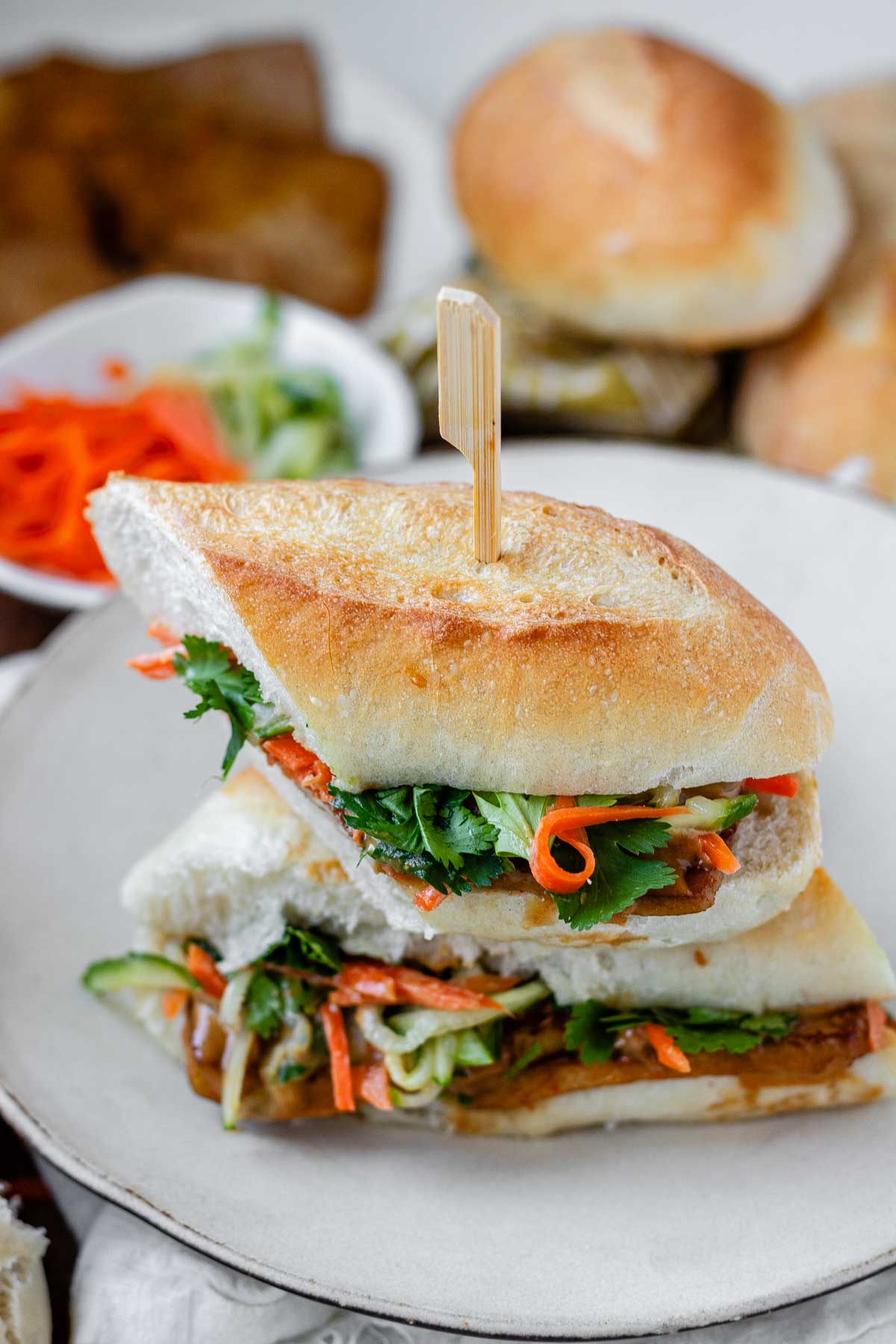 A halved, stacked sandwich with vegetables, tofu, and peanut sauce.