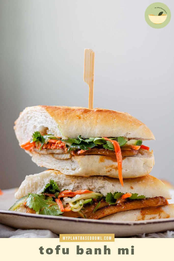 A halved, stacked sandwich with vegetables, tofu, and peanut sauce with the textu tofu banh mi.
