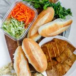 A halved, stacked sandwich with vegetables, tofu, and peanut sauce with the textu tofu banh mi.