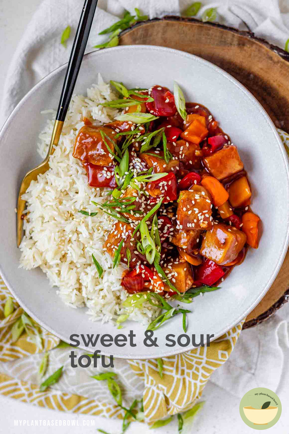 Tofu in sauce in a bowl beside rice, garnished with green onions with the text sweet and sour tofu.